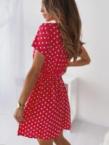 Dettaglio laterale di un abito rosso a pois con scollo a V e maniche corte taglio slim