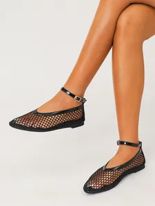 Détail des ballerines en maille noire avec brides de cheville en cuir verni brillant