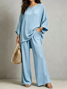 Full lifestyle view showing the draped silhouette of the blue linen top and wide-leg trousers.