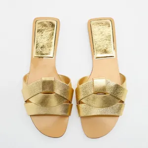Eleganti sandali bassi dorati con punta quadrata e cinturini incrociati da donna.