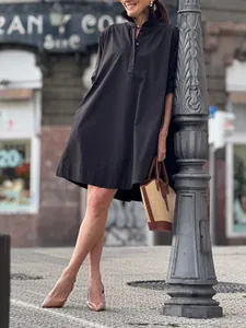 Robe chemise noire évasée coupe ample à manches courtes dans un décor urbain élégant
