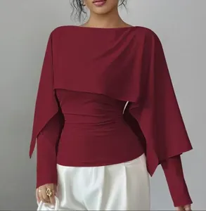 Detalle de top tipo capa burdeos con elegante diseño drapeado y silueta ajustada