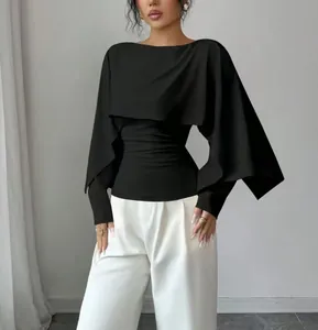 Vista detallada de un top negro estilo capa con cuello redondo y diseño elegante.