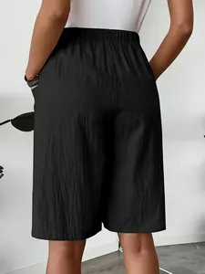 Detail view of women's black high-waisted wide-leg shorts with side pockets and texture.
