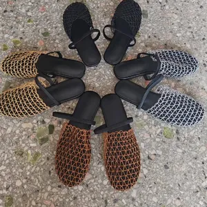 Detailed macro view of hollow mesh woven mules in multiple colors on stone floor