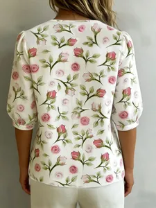 Vista posteriore della camicetta bianca con delicata stampa floreale a rose rosa.