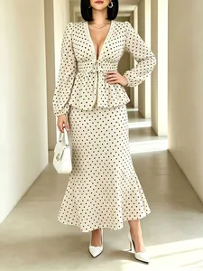 Elegant polka dot V-neck top and mermaid midi skirt set shown on a model in a hallway