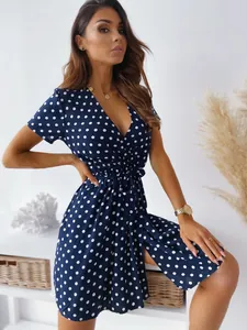 Dettaglio dell'abito a pois blu scuro con scollo a V e cintura in vita.