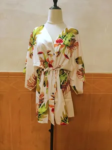 Détail de l'imprimé floral tropical sur une robe chemise blanche ample avec ceinture