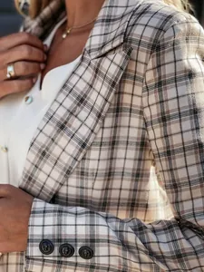 Vista dettagliata di un blazer a quadri beige con bottoni decorativi a testa di leone