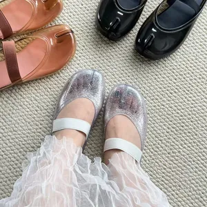 Gros plan de chaussures en PVC à bout fendu élégantes avec une finition pailletée.