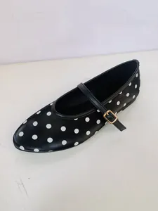 Gros plan de chaussures Mary Jane noires à pois blancs avec une bride à boucle dorée.