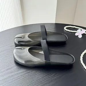 Gros plan de mules noires semi-transparentes à bout fendu avec bride élastique sur table