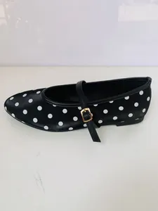 Vue latérale d'une chaussure plate Mary Jane à pois noirs avec bride à boucle