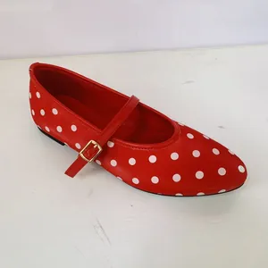 Détail d'une chaussure Mary Jane rouge à pois blancs avec une élégante boucle dorée