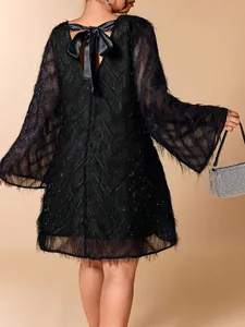 Detail of black fringe dress back featuring a large satin bow and flared bell sleeves.