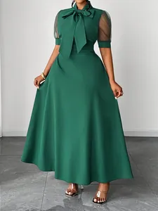 Elegant emerald green mid-length dress featuring a bow collar and sheer mesh sleeves.