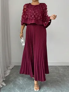 Detail van elegante bordeauxrode geplooide midi-jurk met gebloemde mesh cape-overlay.