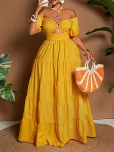 Dettaglio dell'abito lungo giallo a spalle scoperte con ritaglio in vita e gonna a balze.