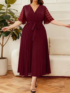 Full body view of elegant burgundy V-neck pleated dress on model in a living room scene