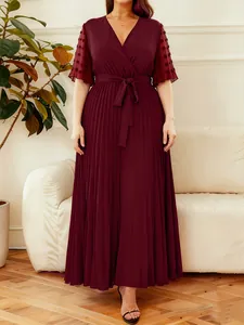 Elegant burgundy V-neck pleated maxi dress with tie waist and sheer polka dot sleeves.