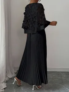 Elegante zwarte jurk achteraanzicht met geplooide rok en mesh bloemencape-detail