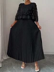 Detail van een elegante zwarte plus size maxi-jurk met mesh cape en 3D bloemapplicaties.