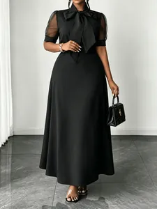 Elegant black midi dress featuring mesh patchwork sleeves and a stylish bow tie neck detail.
