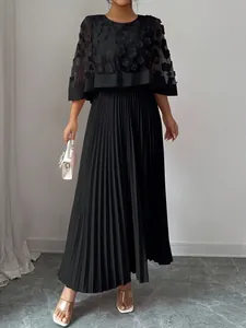 Gedetailleerd overzicht van zwarte midi-jurk met bloemen mesh cape en een geplooide rok