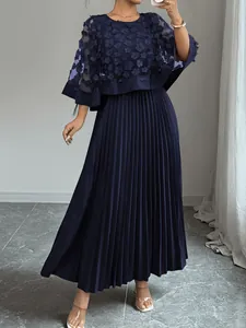 Detailweergave van een elegante marineblauwe jurk met bloemen mesh cape en plissérok