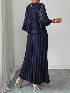 Achteraanzicht van een marineblauwe mesh capejurk met elegante 3D bloemen en plissérok