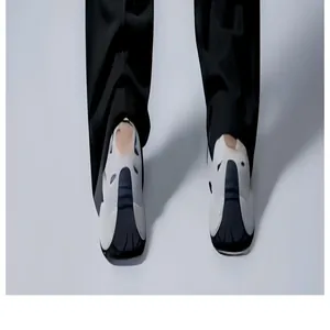 Detailansicht des Saums schwarzer Yoga-Schlaghosen mit weißen futuristischen Clogs.