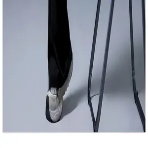 Detailansicht des Saums schwarzer Schlag-Yogahosen mit klobigen weißen Turnschuhen.