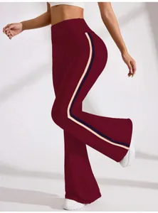Detail view of burgundy flared yoga pants featuring a sporty side stripe and high waistband.