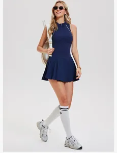 Model wearing navy blue sleeveless tennis dress with pleated skirt and athletic sneakers