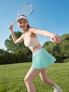 Action-Aufnahme im Freien einer Frau beim Tennis in einem minzgrünen Sport-Faltenrock