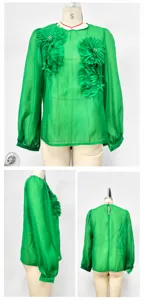 Detailed view of green chiffon blouse with 3D floral appliqués and lantern sleeves