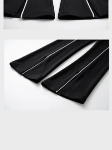 Detailansicht der schwarzen High-Waist-Schlaghose mit weißen Paspeln und Schlitzsaum.