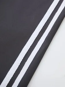 Detailansicht einer High-Waist-Yogahose mit dekorativen weißen Seitenstreifen auf grauem Stoff