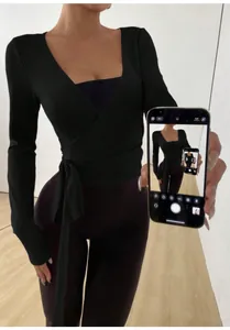 Close-up of a slim fit black wrap-style yoga top featuring an elegant side tie detail