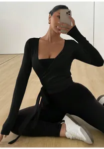 Side view of professional athlete in black long sleeve wrap yoga top with elegant tie detail