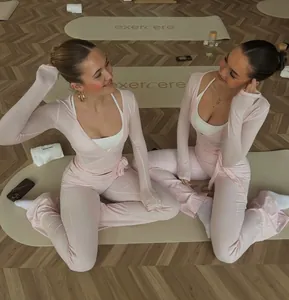 Two fitness women wearing pink ballet-style yoga sets in a professional Pilates studio room
