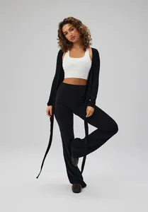 Model wearing black ballet style tie-front long sleeve yoga cover-up over white top
