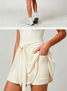 Detail view of cream tennis dress featuring functional side pocket and tie-waist