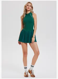 Full body view of a dark green sleeveless tennis dress with pleated skirt on a model.
