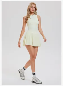 Full-length view of a model in a pale yellow half-zip sleeveless tennis pleated dress
