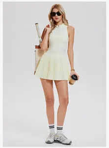 Detail view of the model wearing a pale yellow half-zip tennis dress with pleated skirt