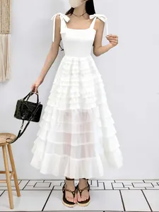 Detailed shot of an elegant white sleeveless tiered tulle A-line midi dress with shoulder ties