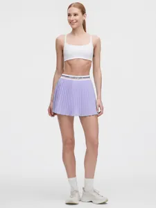 Vollständige Ansicht eines Models in einem lila gefalteten Sport-Skort für Tennis