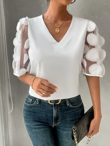 Detail view of a white V-neck blouse featuring sheer bubble sleeves with 3D dot embroidery.